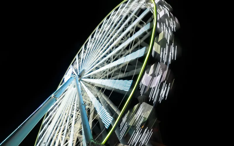 Ferris wheel captured with a slow shutter speed, creating a smooth circular light blur