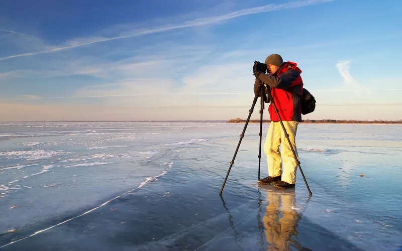 photographer setting Camera tripod for a stable long exposure shot near ocean