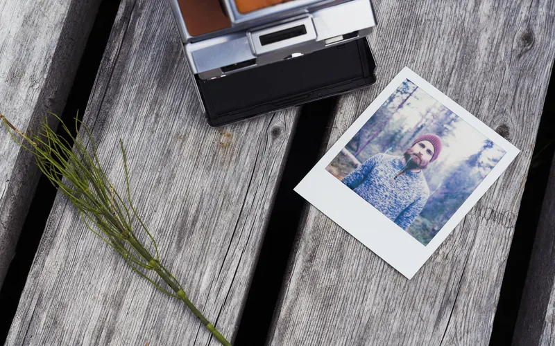 polaroid photo of a man kept on wooden table along with desk