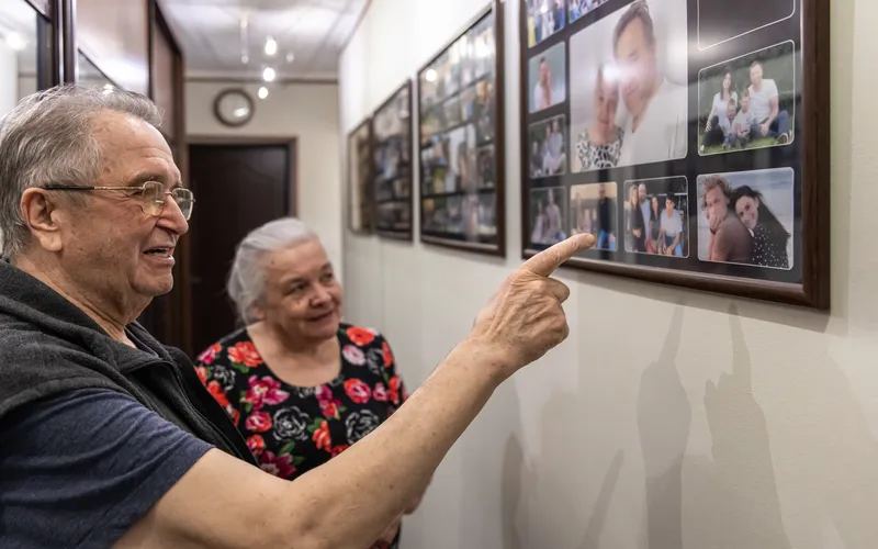 senior man pointing at wall decoration with photo of deceased one