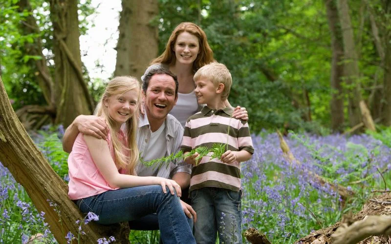 Family of four sitting together outdoors among purple wildflowers, a family portrait aperture example