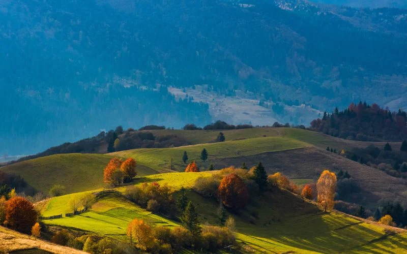Wide landscape view of green rolling hills and a valley under a blue sky, shot with a small aperture for full depth of field