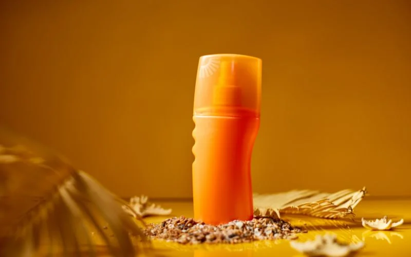 Orange product bottle photographed on a warm amber background with dried leaves, a product photography aperture example