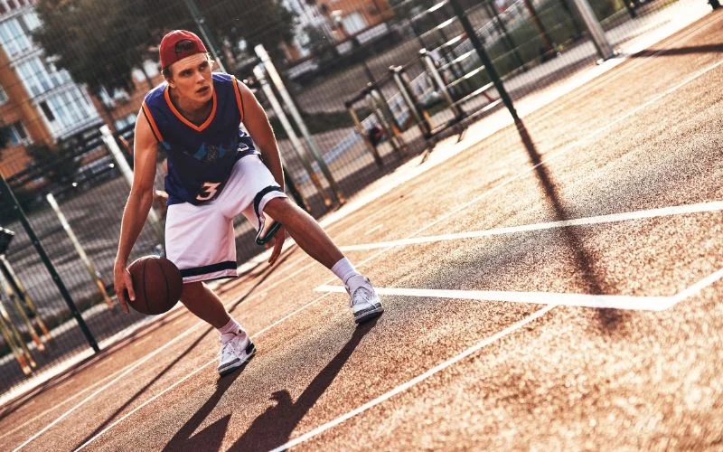 Basketball player dribbling on an outdoor court captured mid-action, a sports photography aperture example
