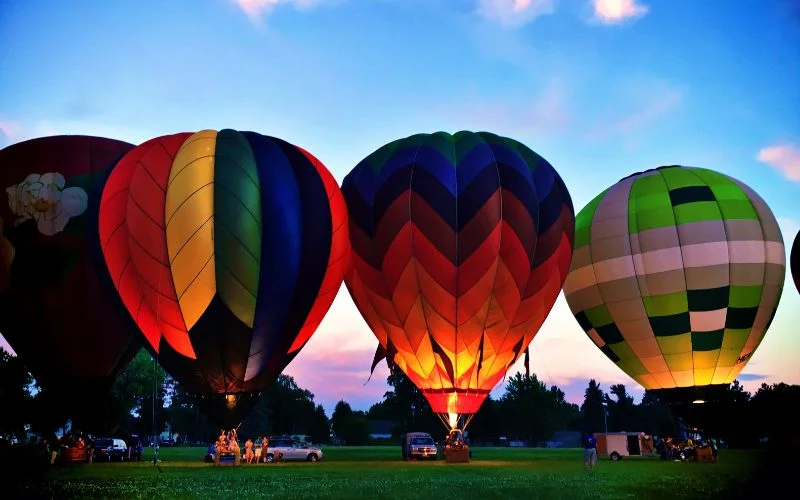 Row of colorful hot air balloons glowing at dusk, illustrating what does aperture affect in terms of exposure and brightness