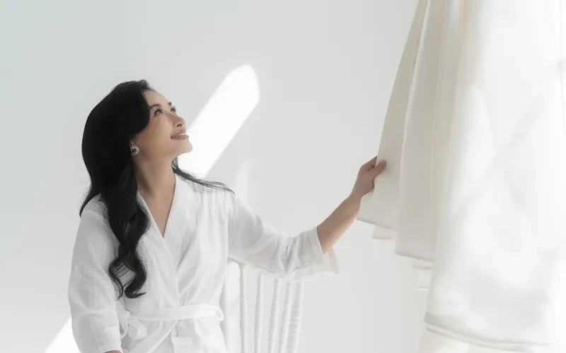 woman in a bath robe looking at a dress in high key lighting