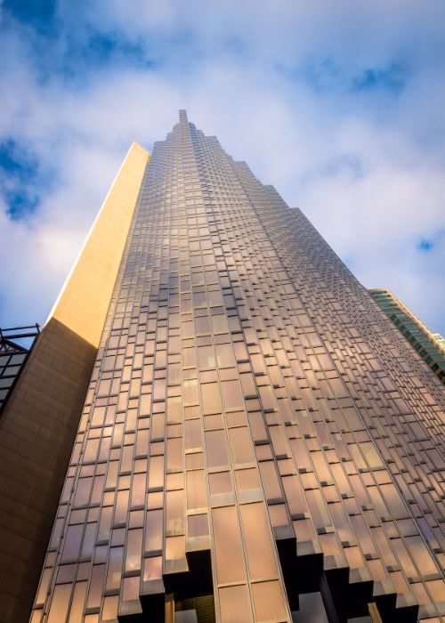 Low-angle architectural photograph of a modern skyscraper against a cloudy sky, demonstrating the artistic perspective that shapes the future of photography.