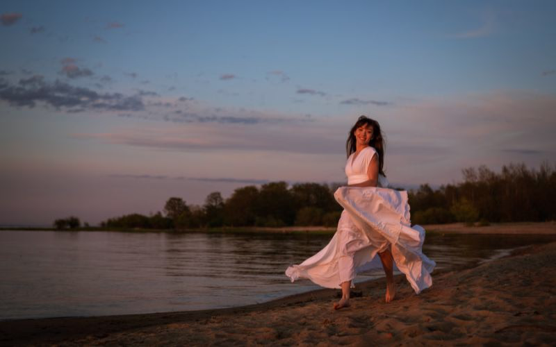 Solo photoshoot of a woman twirling in her flowy dress on the beach