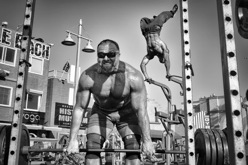 Athlete lifting weights captured using street photography techniques in an outdoor gym.