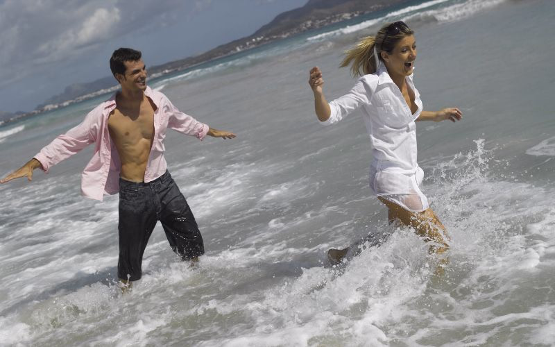 beach photography of couple chasing each other through the waves