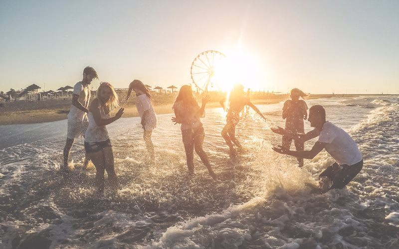 Beach photoshoot of friends splashing each other with water