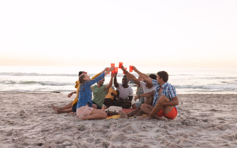 Friends toasting their drinks on the beach to pose for their beach photoshoot