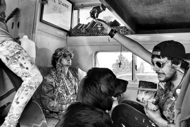 Candid black-and-white street photography of travelers sharing a moment inside a vehicle.