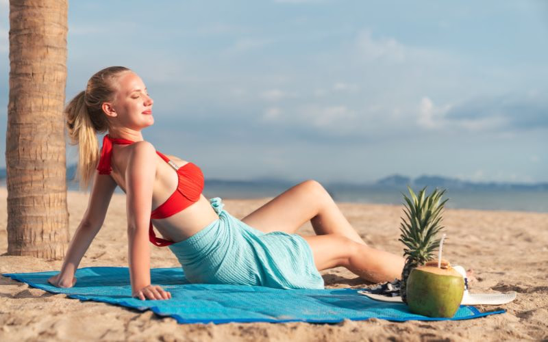 A woman lying on the beach while leaning on her palms