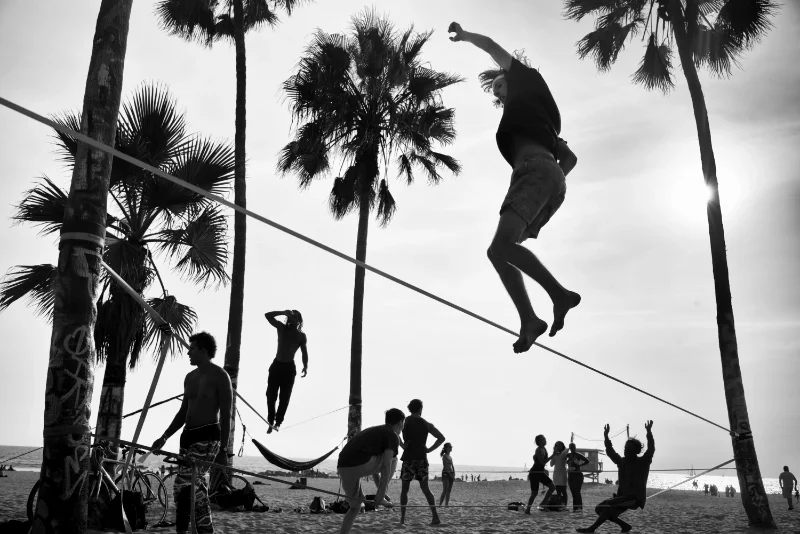 Slackliner performing in a public park photographed during a street photography course online.