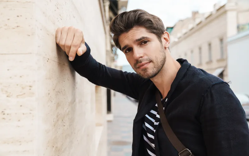 handsome man posing while leaning against a wall