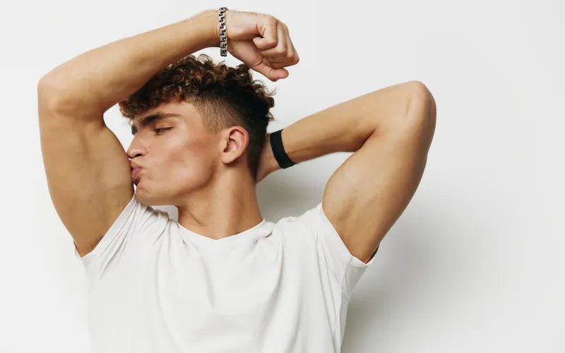 man in curly hair posing for a photo while flexing his jawline